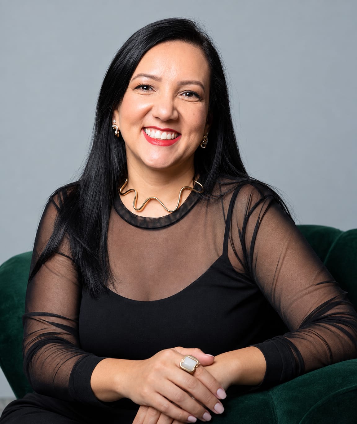 Retrato de Lilian Lima, psicóloga, sentada em uma poltrona verde